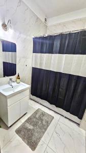 een badkamer met een wastafel en een blauw douchegordijn bij - Cozy Apartment in Quite Area - in Tasjkent
