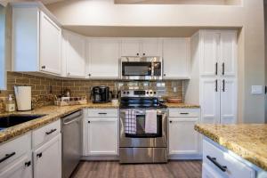 uma cozinha com armários brancos e um forno de aço inoxidável em Luxe Phoenix Getaway (heated pool, mountain view) em Phoenix