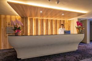 a man standing behind a reception desk with a laptop at Hotel Cocoa - Vacation STAY 24777v in Sakura