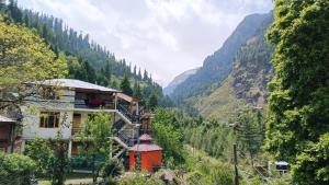 una casa in una valle con montagne sullo sfondo di The Mystic Heaven a Manāli