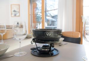 a pot on a stove with wine glasses on a table at Holiday flat for 6 people Sot Valos Lenzerheide centre in Lenzerheide