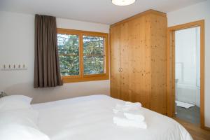 a bedroom with a white bed and a window at Holiday flat for 6 people Sot Valos Lenzerheide centre in Lenzerheide