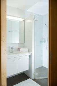 a white bathroom with a sink and a shower at Holiday flat for 6 people Sot Valos Lenzerheide centre in Lenzerheide