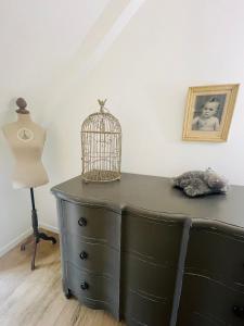 a black dresser with a bird cage on top of it at Le Clos des Anges, adorable Penty bord de mer in Séné