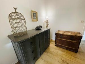 une commode noire avec une cage pour oiseaux et un coffre en bois dans l'établissement Le Clos des Anges, adorable Penty bord de mer, à Séné