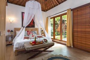 Schlafzimmer mit einem Bett mit Moskitonetz in der Unterkunft Ubud Raya Villa in Ubud