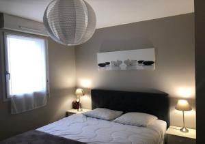 a bedroom with a bed and two lamps and a window at Les cottages du golf in Le Tronchet