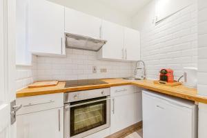 una cocina blanca con armarios blancos y fregadero en The Knightsbridge Deluxe Apart en Londres
