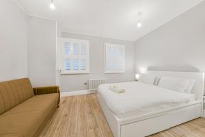 a white bedroom with a bed and a couch at The Knightsbridge Deluxe Apart in London