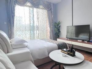 a bedroom with a bed and a tv and a table at 广州沃家国际公寓 in Guangzhou