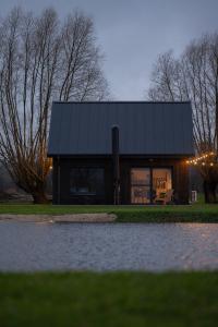 a house with a black roof next to a pond at Daczowisko in Gruczno