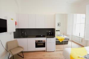 eine Küche mit weißen Schränken und einem Stuhl in einem Zimmer in der Unterkunft Kensington Studios in London