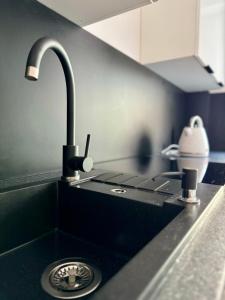 a kitchen sink with a black counter and a sink at Apartament Ula in Nysa