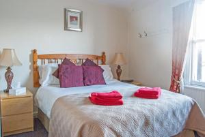 a bedroom with a bed with two red towels on it at Crown and Anchor Inn in Findhorn