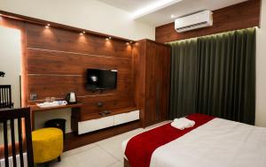 hotel 24inn residency في Pathanāmthitta: غرفة فندقية بسرير وتلفزيون بشاشة مسطحة