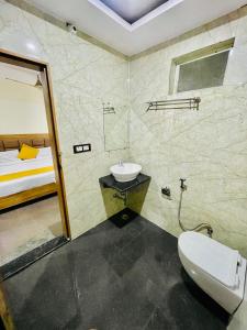 a bathroom with a sink and a toilet and a bed at Hotel Skylight Silverkey by Madhav in Mathura