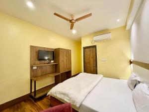 ein Schlafzimmer mit einem Bett und einem TV. in der Unterkunft Hotel SHIVAM ! Varanasi Forɘigner's-Choice ! fully-Air-Conditioned-hotel, lift-and-Parking-availability near-Kashi-Vishwanath-Temple and-Ganga-ghat in Varanasi