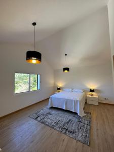 a white bedroom with a bed and two lamps at The Passion Fruit House in São Vicente