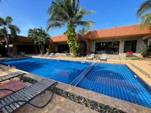 ein Pool mit zwei Stühlen und ein Gebäude in der Unterkunft Chill Villa in Ban Pak Nam Pran