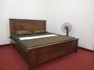 Ce lit en bois se trouve dans un dortoir doté d'un ventilateur. dans l'établissement Idom Cozy, à Gampola