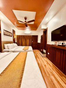 a bedroom with two beds and a flat screen tv at Walisons Hotel in Srinagar