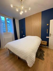 um quarto com uma cama branca e uma parede azul em Spa jacuzzi Caen centre em Caen