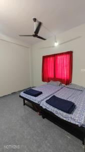 Aadishkti bhakt nivas في Tuljapur: غرفة نوم بسرير وستارة حمراء