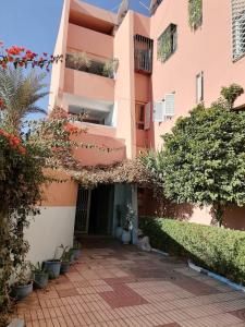 un edificio rosa con un patio con plantas en Julie's AIRPORT Apartment en Marrakech
