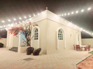 Villa 9 Palms Beach في رأس الخيمة: مبنى أبيض به طاولة وكراسي وأضواء