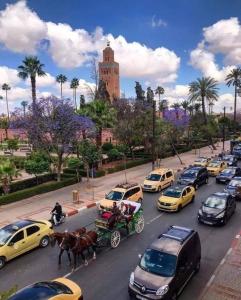 een drukke stadsstraat met auto's en een paardenkoets bij Julie's AIRPORT Apartment in Marrakesh