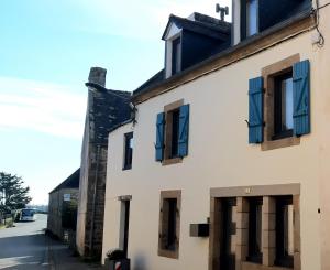 Poullan-sur-MerGite aux portes de la Pointe du Raz的白色的建筑,在街上有蓝色百叶窗
