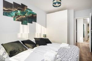 ein Schlafzimmer mit einem weißen Bett und einem Gemälde an der Wand in der Unterkunft Capital Apartments in Krakau