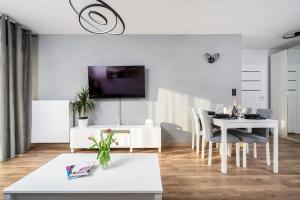 ein weißes Wohnzimmer mit einem Tisch und einem TV in der Unterkunft Capital Apartments in Krakau
