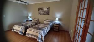 três camas num quarto com duas mesas e duas lâmpadas em Pabala Private Nature Reserve em Hankey