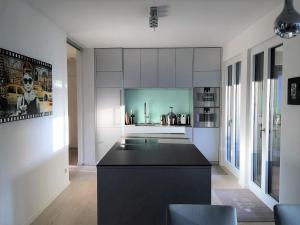 a kitchen with white cabinets and a black island at Luxury 2-Bedroom Flat close to FAIR & OLD TOWN in Düsseldorf