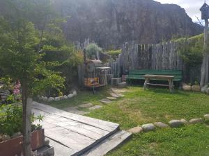 un jardín con un banco verde y una valla en EL Carpintero en El Chaltén