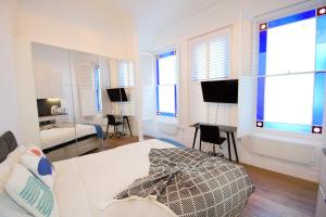 1 Schlafzimmer mit einem Bett, einem Schreibtisch und 2 Fenstern in der Unterkunft Kensington Studios in London