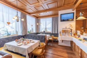 ein Restaurant mit Tischen und Stühlen sowie einem TV in der Unterkunft Hotel Garni Helvetia in Ischgl