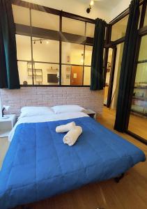 ein großes Bett mit einer blauen Decke drauf in der Unterkunft Industrial Design Loft near City Center and Stadium in Bologna