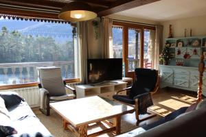 a living room with a couch and chairs and a television at El Balcón del Garmo in Sallent de Gállego