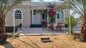 Villa 9 Palms Beach في رأس الخيمة: فناء مع كراسي وطاولة أمام المنزل