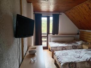 a room with two beds and a flat screen tv at Apartmani - Mesko vajat in Divčibare