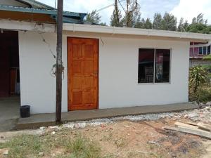 een wit huis met een bruine deur erop bij Raniah Homestay2 in Kuching
