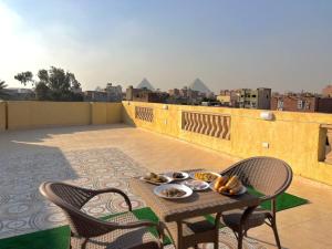 a table and chairs on a balcony with a view at Nefertiti guest house view pyramids in Cairo