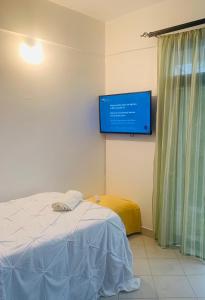 Cette chambre comprend un lit et une télévision murale. dans l'établissement Moraa’s Home, à Mombasa