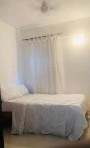 - une chambre avec 2 lits avec des draps blancs et une fenêtre dans l'établissement Moraa’s Home, à Mombasa