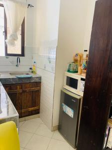 a kitchen with a microwave and a refrigerator at Moraa’s Home in Mombasa
