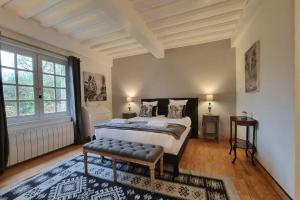 a bedroom with a large bed with a bench in it at Maddalena - Charming country villa for 10 people in Barneville-la-Bertran