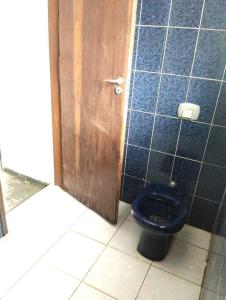 a bathroom with a blue toilet and a wooden door at Casa mobiliada individual in Campinas