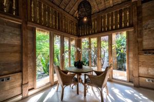 a dining room with a table and chairs and windows at Villa Sayang in Nusa Lembongan